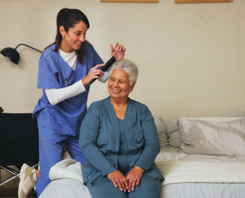 senior women getting her hair brushed by home health aide.